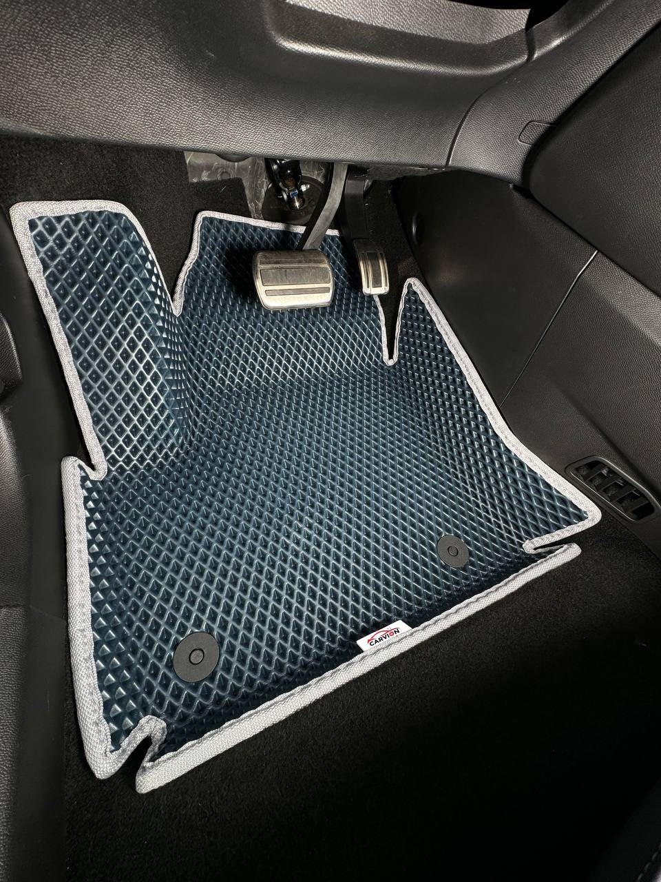 Foto ilustrativa: alfombrilla EVA 3D azul marino con bordes elevados y ribete gris en el espacio para los pies del conductor